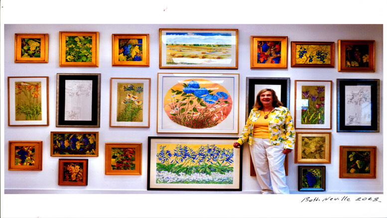 A woman standing beside a wall displaying various colorful framed paintings and sketches from the 'Making Waves' exhibit by Artist John Anthony Lawrence, with a signature and date in the corner.