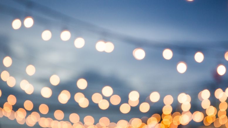 Blurred image of round string lights hanging against a dusky sky, reminiscent of the enchanting evenings at BarnFest.