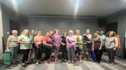 A group of people standing in a room at the Milton Public Library, holding yoga mats and smiling at the camera, showcases enthusiasm for adult programs announced for November 2024.