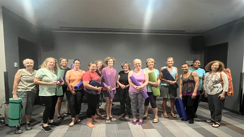 A group of people standing in a room at the Milton Public Library, holding yoga mats and smiling at the camera, showcases enthusiasm for adult programs announced for November 2024.