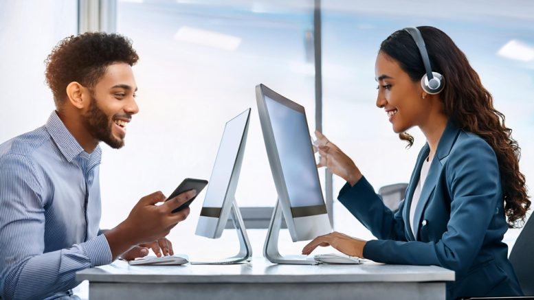 At Small Business Corner, two people collaborate at a desk, eyes glued to computer screens. One is tapping on their smartphone while the other wears headphones and explores a tablet, showcasing how small businesses can turn comments into meaningful connections and drive sales.