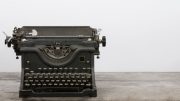 An old black typewriter sits on a wooden surface against a plain white background—a timeless relic, ready to inspire new tales at the Intro to Freelance Writing workshop with Calvin Hennick on November 19, 2024.