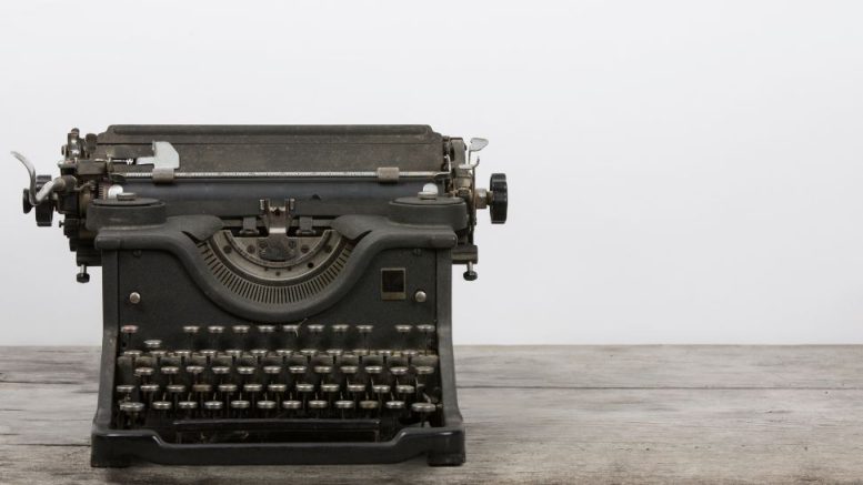 An old black typewriter sits on a wooden surface against a plain white background—a timeless relic, ready to inspire new tales at the Intro to Freelance Writing workshop with Calvin Hennick on November 19, 2024.