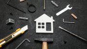 Assorted tools and a house-shaped cutout arranged on a dark background.