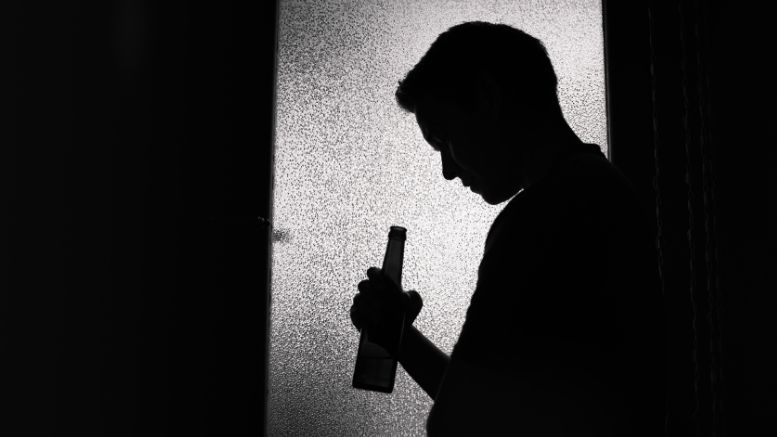 Silhouette of Milton student Angela Truong holding a bottle, standing in front of a textured glass window, illustrating her commitment to educating policymakers on the importance of alcohol misuse prevention.