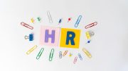 Colorful paperclips, push pins, and binder clips surround "HR" in bold letters on pink and yellow backgrounds, highlighting HR best practices essential for effective management in large workplaces.