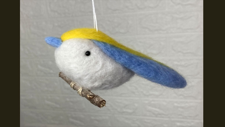 A charming wool felt bird ornament with blue and yellow wings, perfect for adding a touch of whimsy to your 2025 celebrations. This delightful piece hangs gracefully from a string, making it an ideal gift for the boozy bookworms meetup at Steel & Rye on March 27.